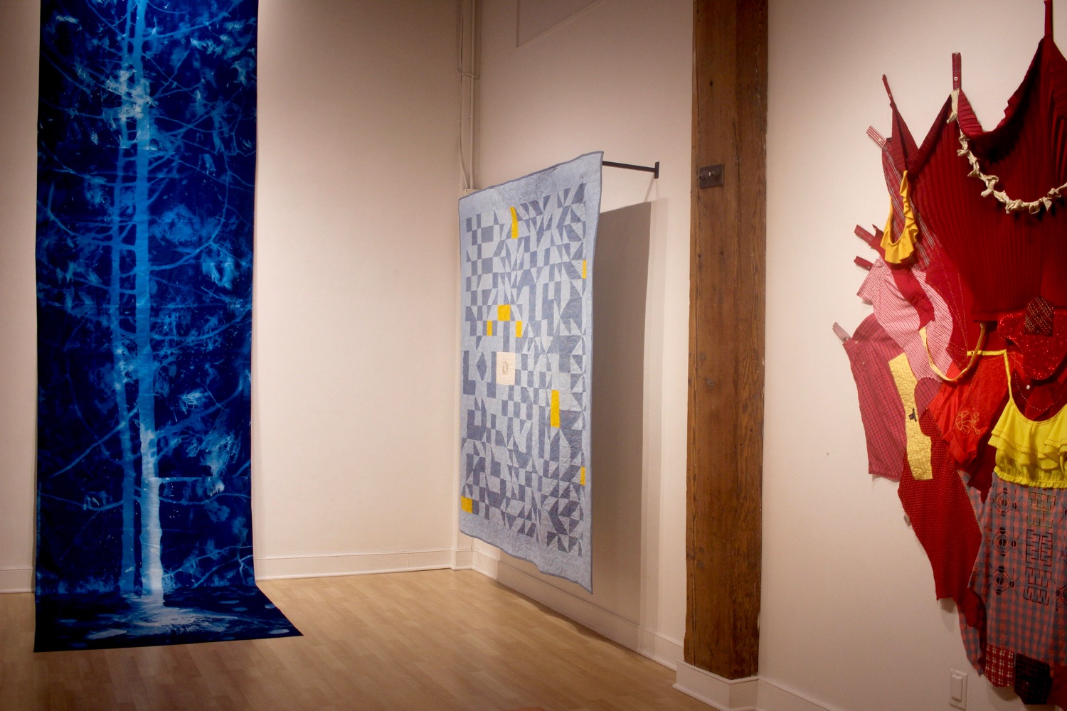 Three fabric artworks hanging in an art gallery