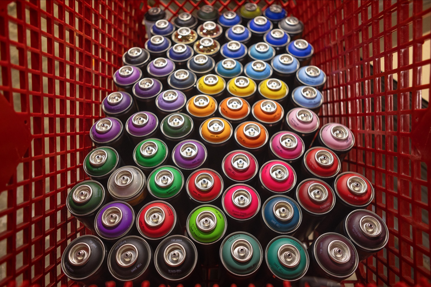 A red basket full of spray paint cans