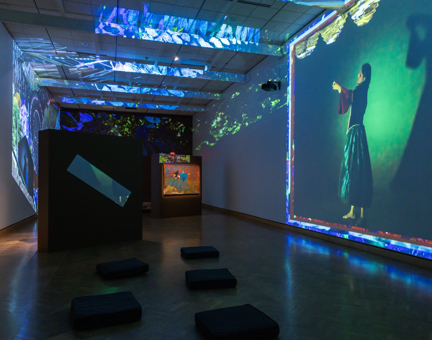 Gallery installation of projections featuring a dancing woman and cushions on the floor