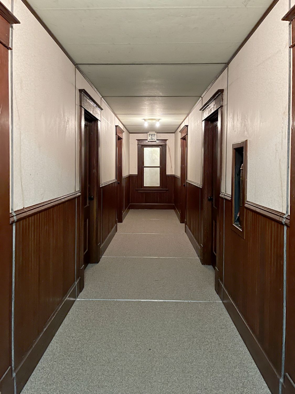 View down a long, nondescript apartment hallway with wooden doors