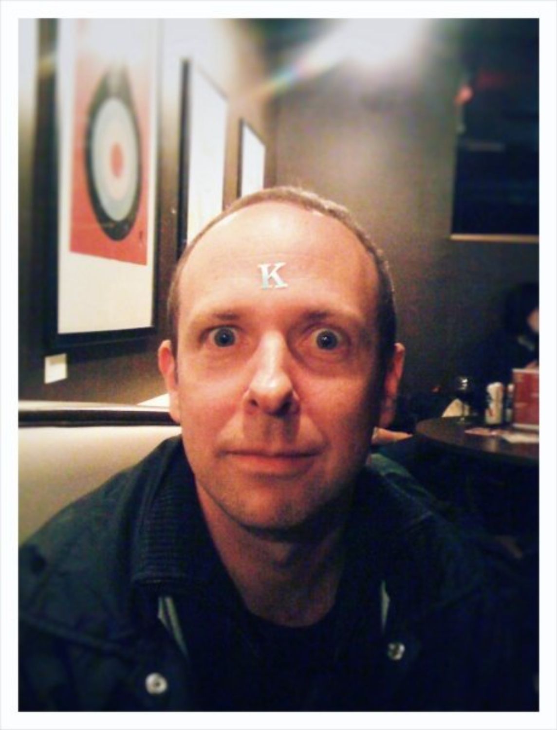Man at diner with silver letter K on his forehead