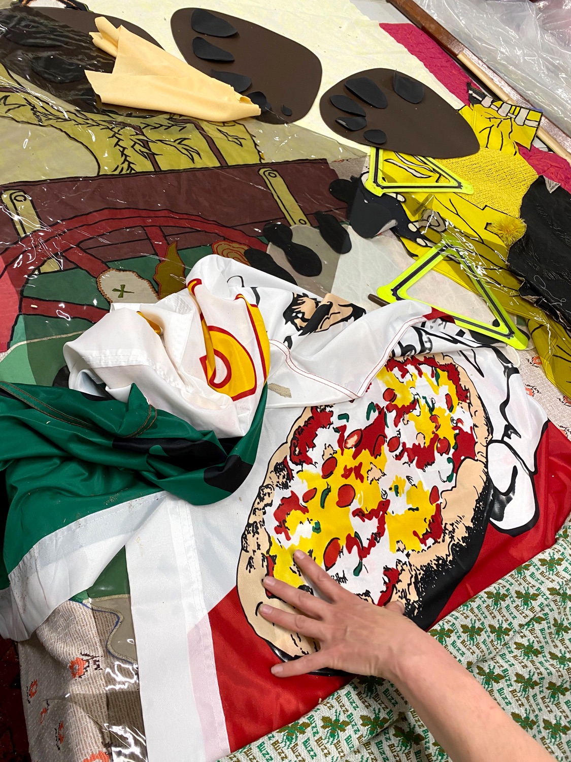 Hand points to a cartoon pizza on a table of fabric scraps