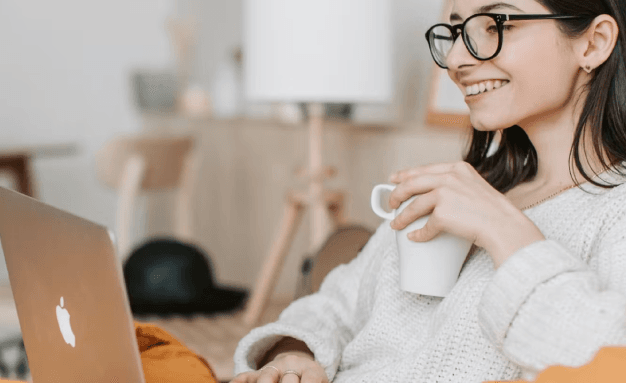 A smiling woman shops online on her computer