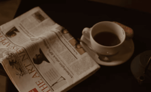 A cup of coffee next to a newspaper