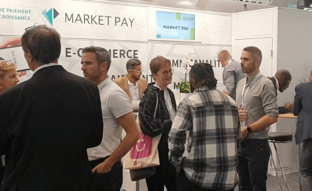 Several people talking on the Market Pay stand at Paris Retail Week