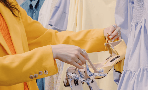 A woman is comparing two pairs of shoes in a store