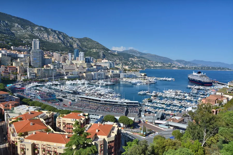 Panoramic view of Monaco’s harbor during race week, packed with yachts, stands, and a cruise ship anchored at the port. Panoramic view of Monaco’s harbor during race week, packed with yachts, stands, and a cruise ship anchored at the port.