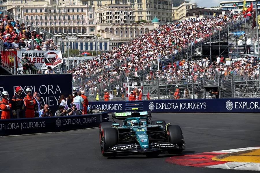 Close-up of Monaco Grand Prix race stands with fans, Explora Journeys signage, and yachts visible in the background. Close-up of Monaco Grand Prix race stands with fans, Explora Journeys signage, and yachts visible in the background.