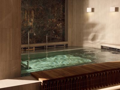 Luxurious indoor spa pool with warm lighting, stone walls, and modern water features, creating a serene wellness retreat. Luxurious indoor spa pool with warm lighting, stone walls, and modern water features, creating a serene wellness retreat.