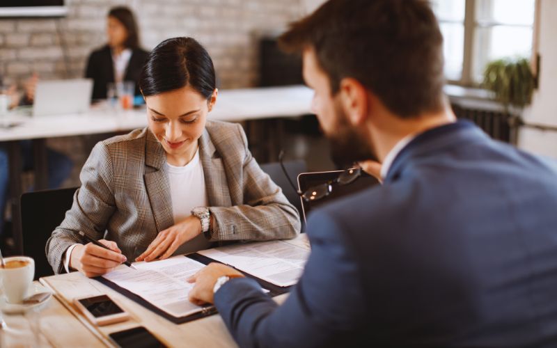Woman sitting with bank representative to sign a loan agreement.