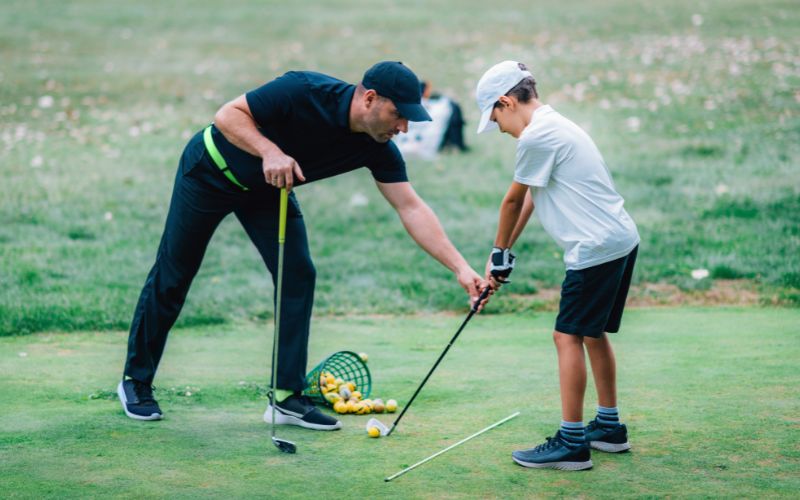 Man teaching grandchild how to play golf