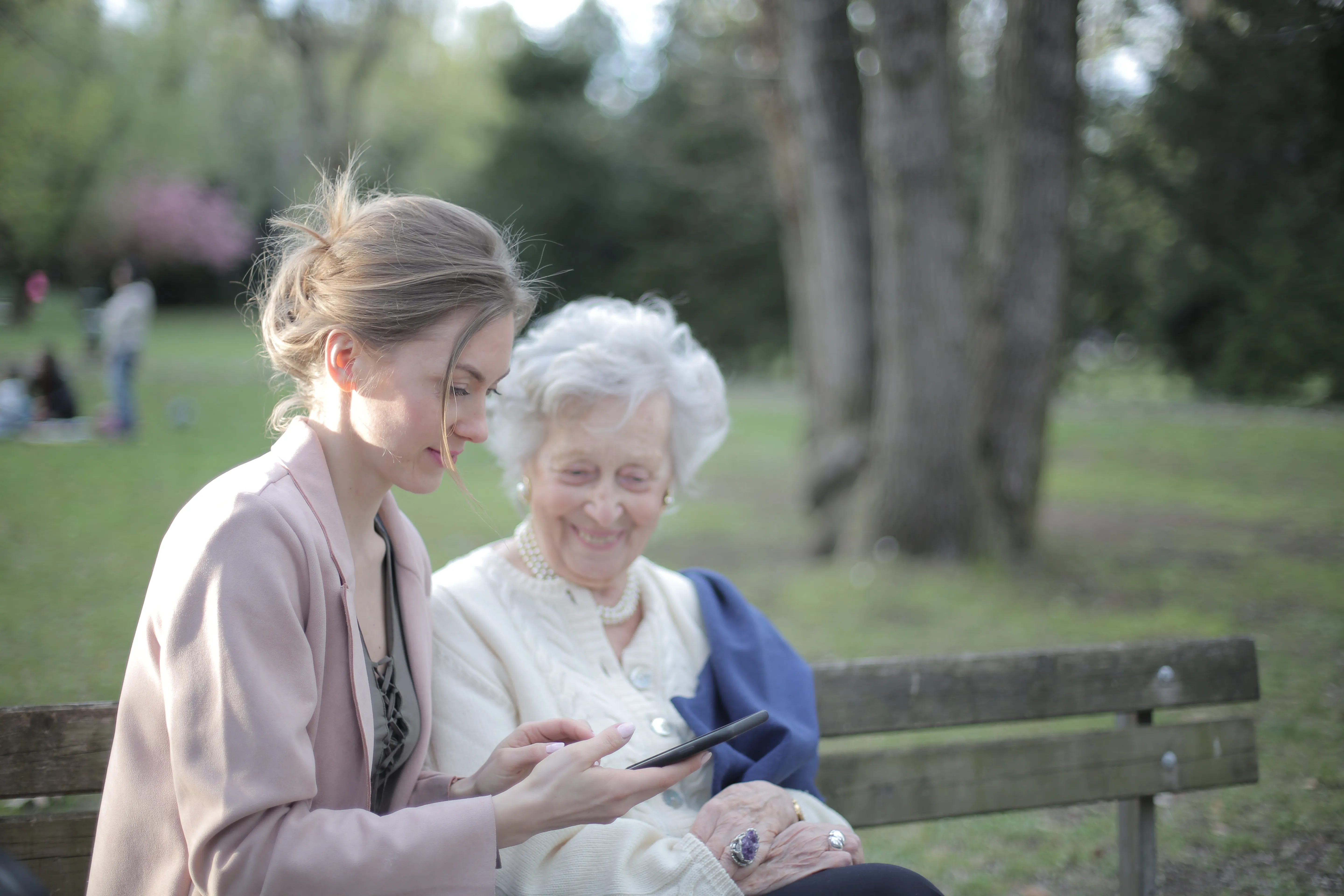 elderly lady checking a phone with a younger lady