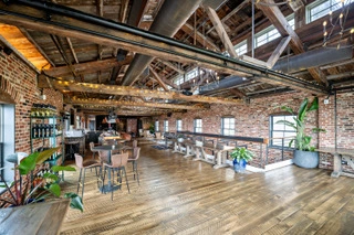 Spacious loft-style venue space in Virginia with exposed brick walls, wooden floors, high ceilings, large windows, tables, chairs, potted plants, and a bar area—perfect for hosting your micro-wedding or intimate event. Spacious loft-style venue space in Virginia with exposed brick walls, wooden floors, high ceilings, large windows, tables, chairs, potted plants, and a bar area—perfect for hosting your micro-wedding or intimate event.