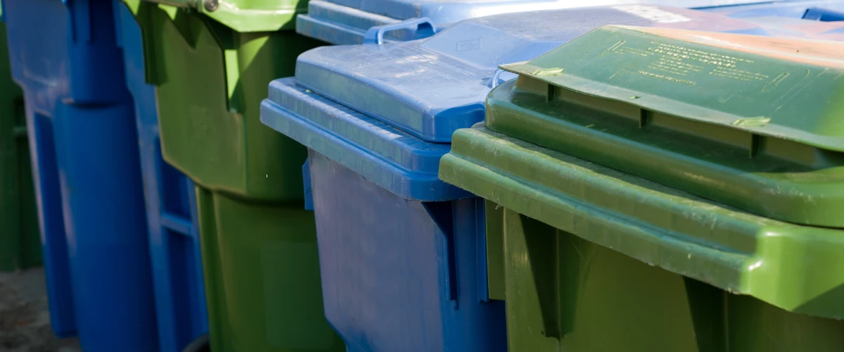 Row of blue and green recycling and trash bins outdoors Row of blue and green recycling and trash bins outdoors