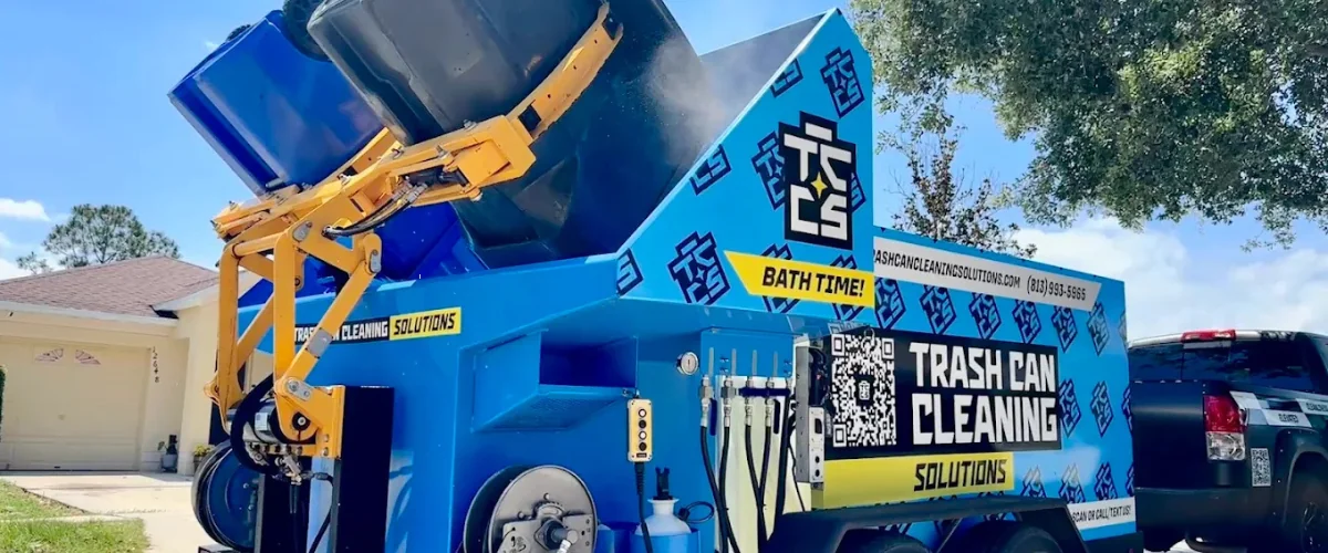 Professional trash can cleaning truck sanitizing garbage bins curbside with high-pressure system.
