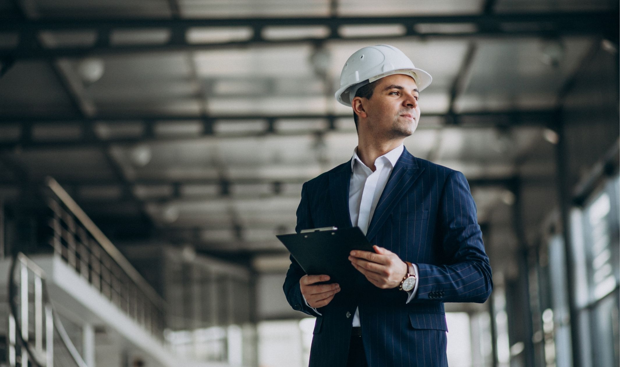 A business man wearing a hard hat and going over a launch checklist for digital entrepreneurs on a clipboard A business man wearing a hard hat and going over a launch checklist for digital entrepreneurs on a clipboard