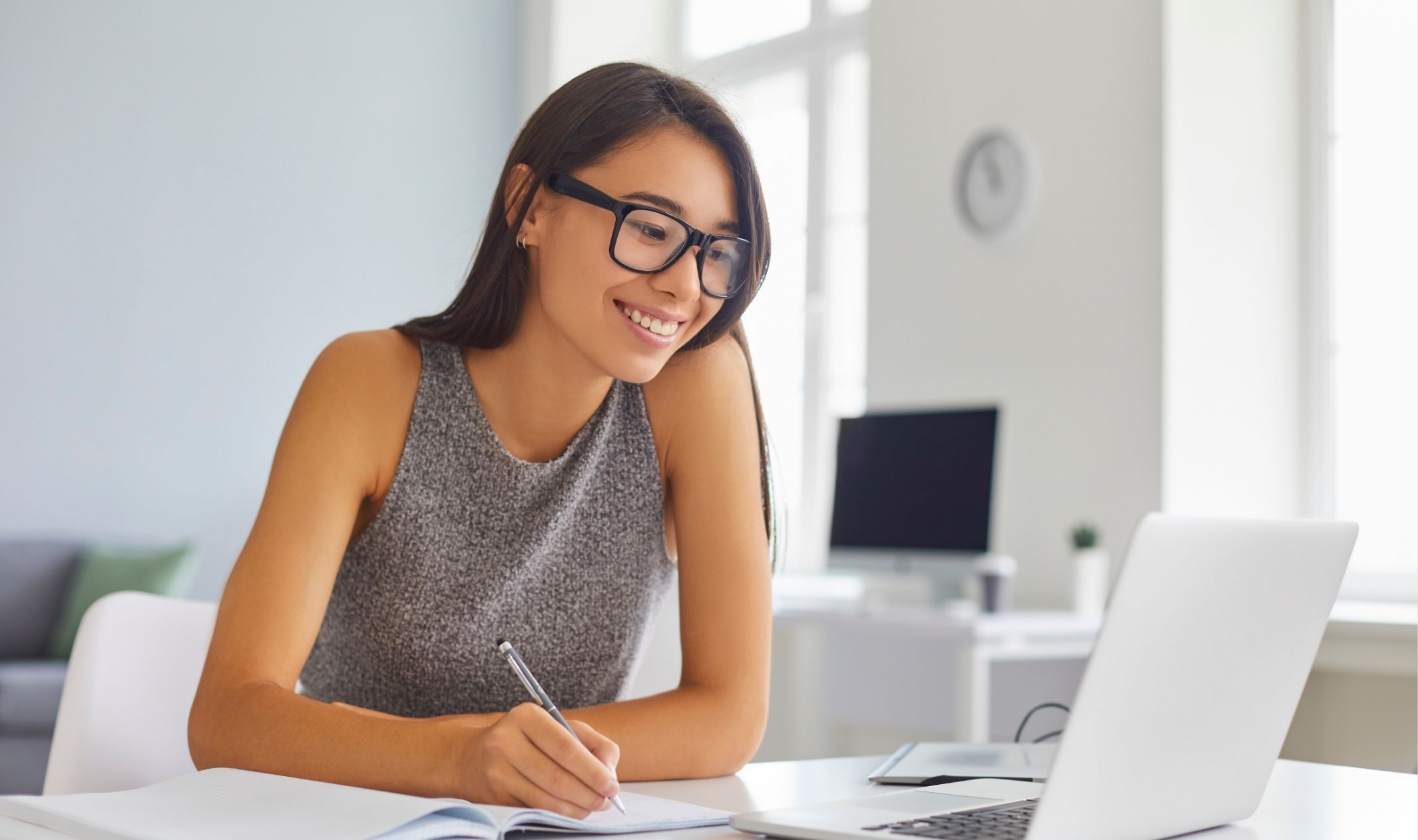 A business woman planning out her online business first year workload on her laptop and notepad A business woman planning out her online business first year workload on her laptop and notepad