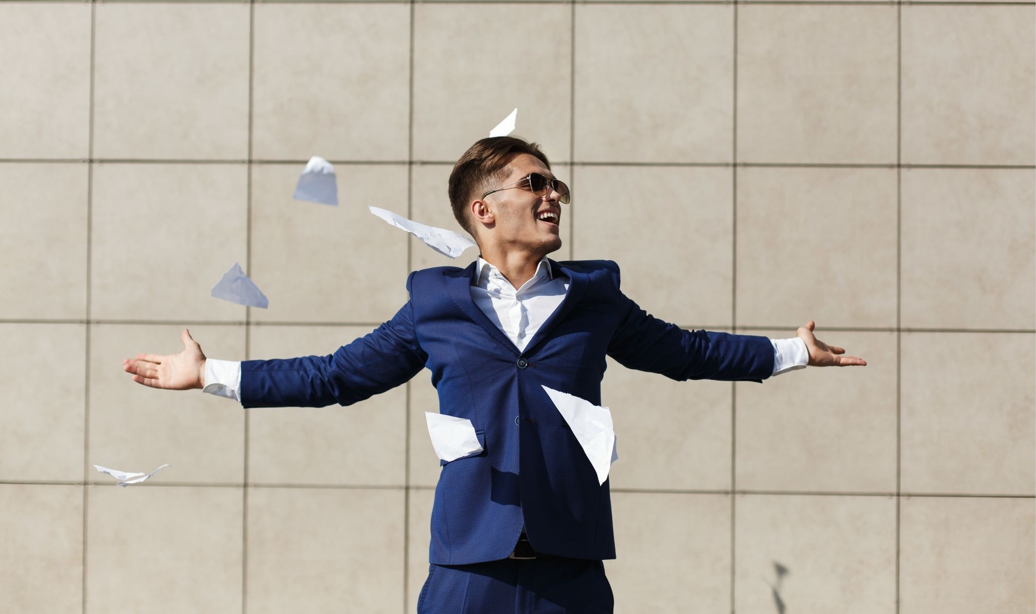 A business owner celebrating with his arms stretched outward and papers thrown around him because he achieved freedom through automation A business owner celebrating with his arms stretched outward and papers thrown around him because he achieved freedom through automation