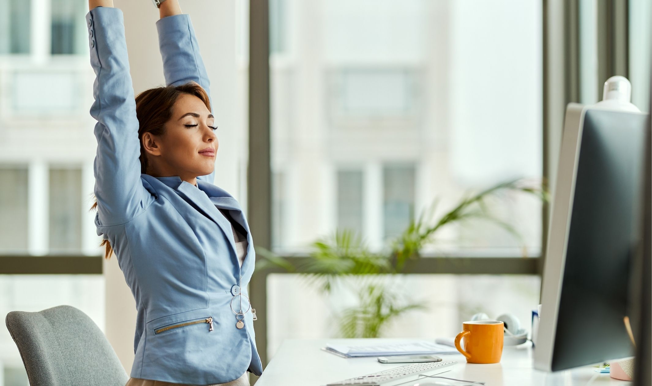 A business woman stretching at her desk after using her computer to set up Go HighLevel automation tools A business woman stretching at her desk after using her computer to set up Go HighLevel automation tools