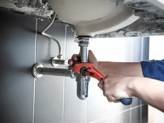 an expert plumber fixing the pipes under the sink.