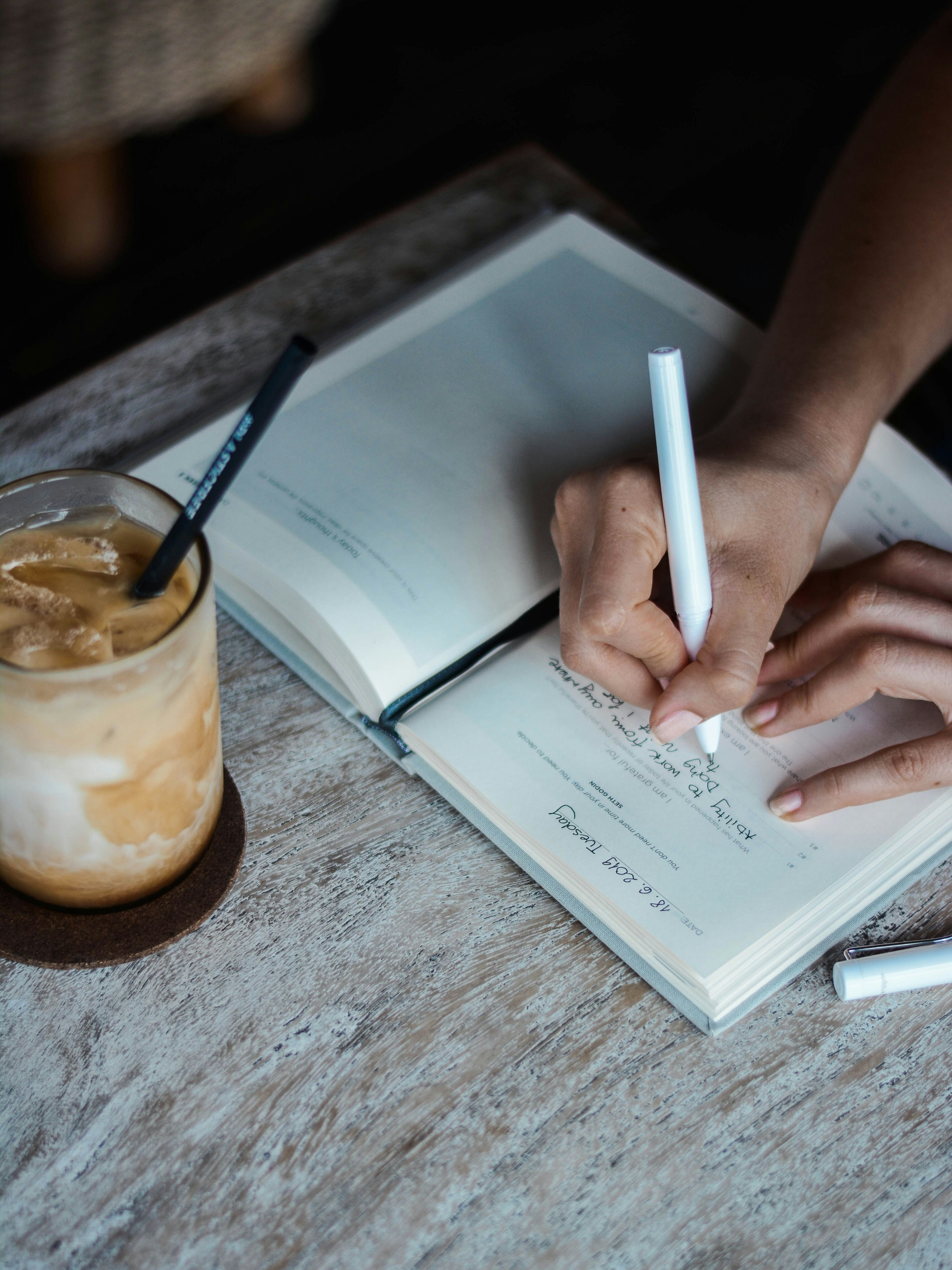 journal on desk beside iced coffee journal on desk beside iced coffee