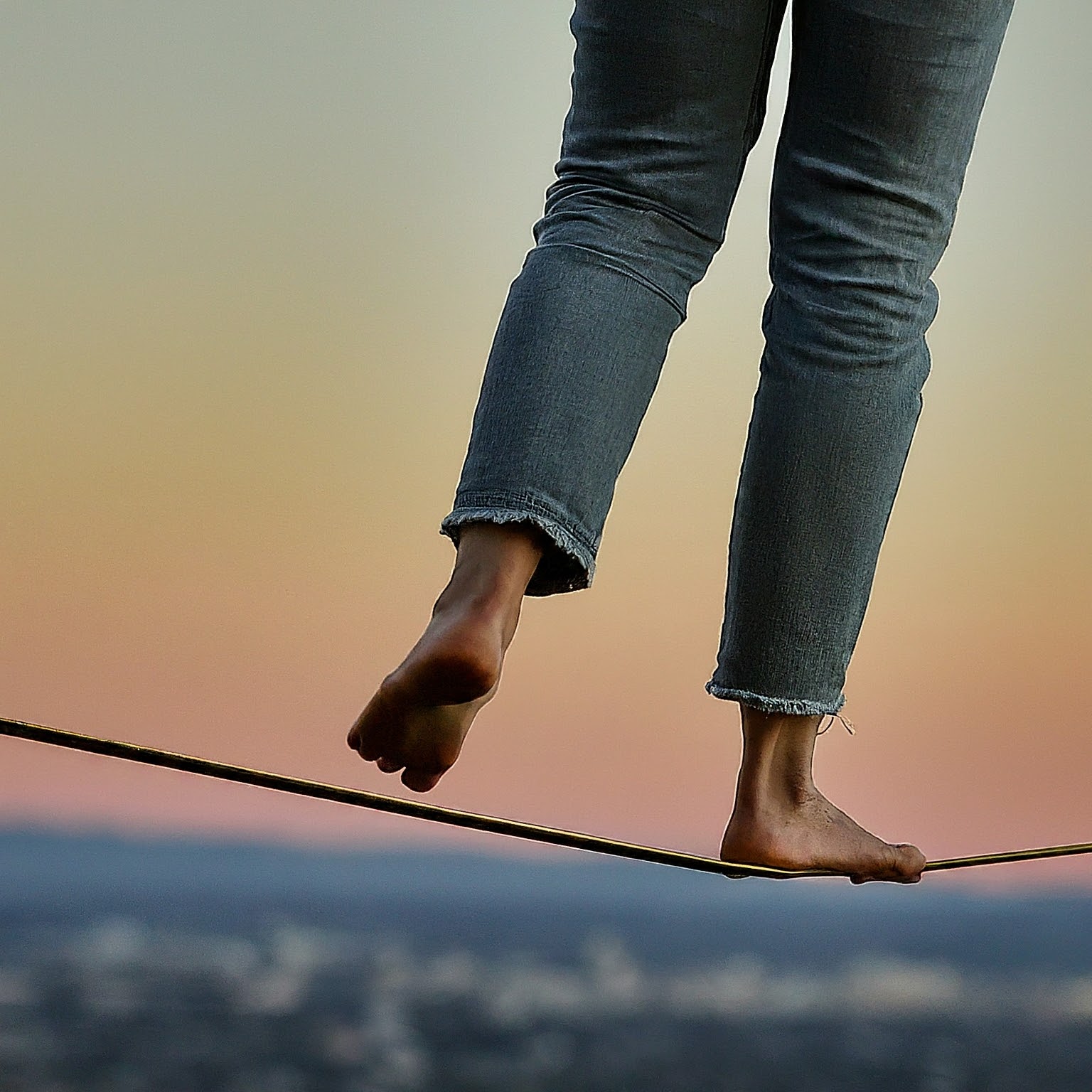 person in jeans walking on tight rope 