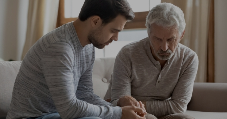 father and son sitting together holding hands at home