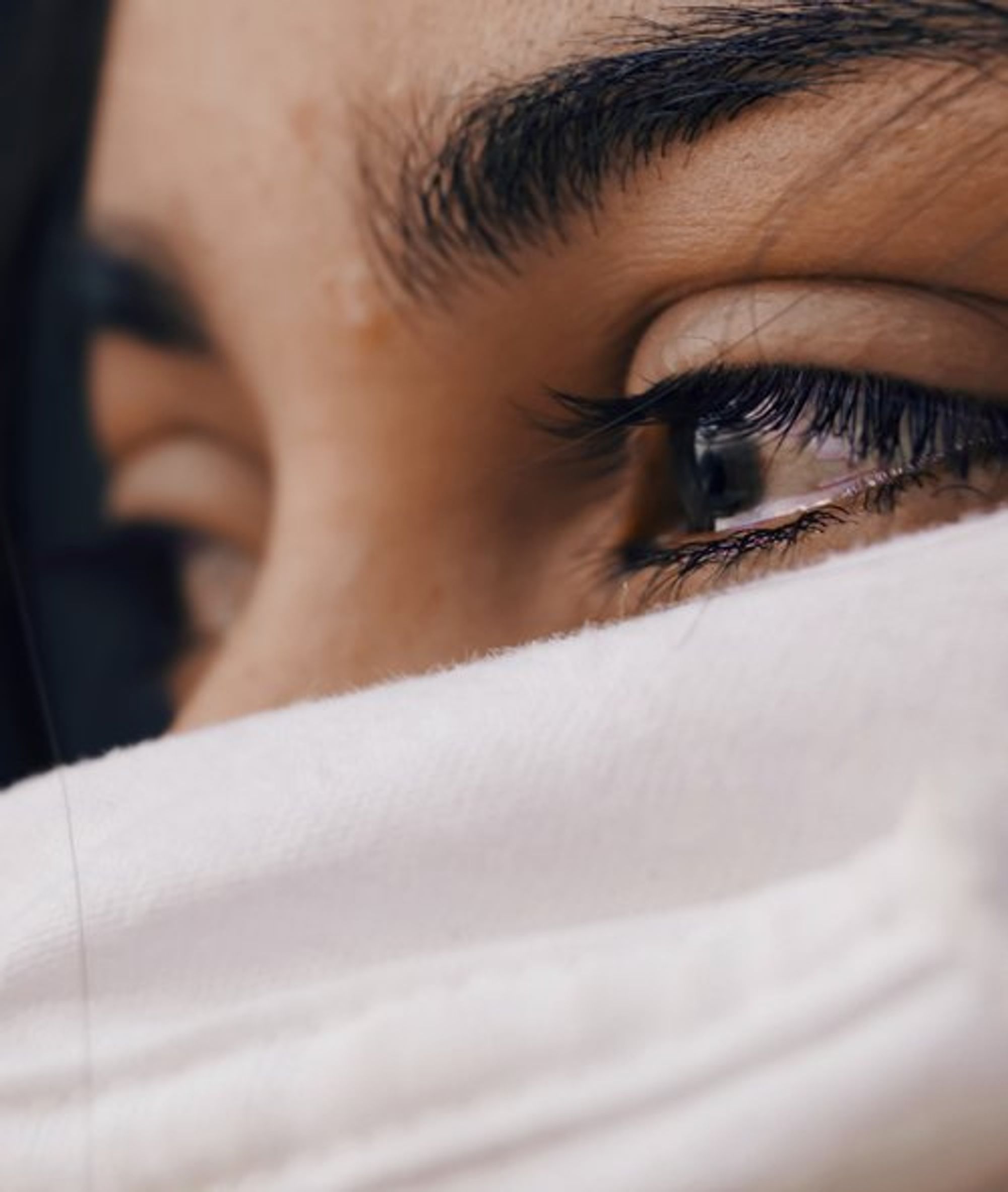 close up of a woman's face behind a hoodie crying