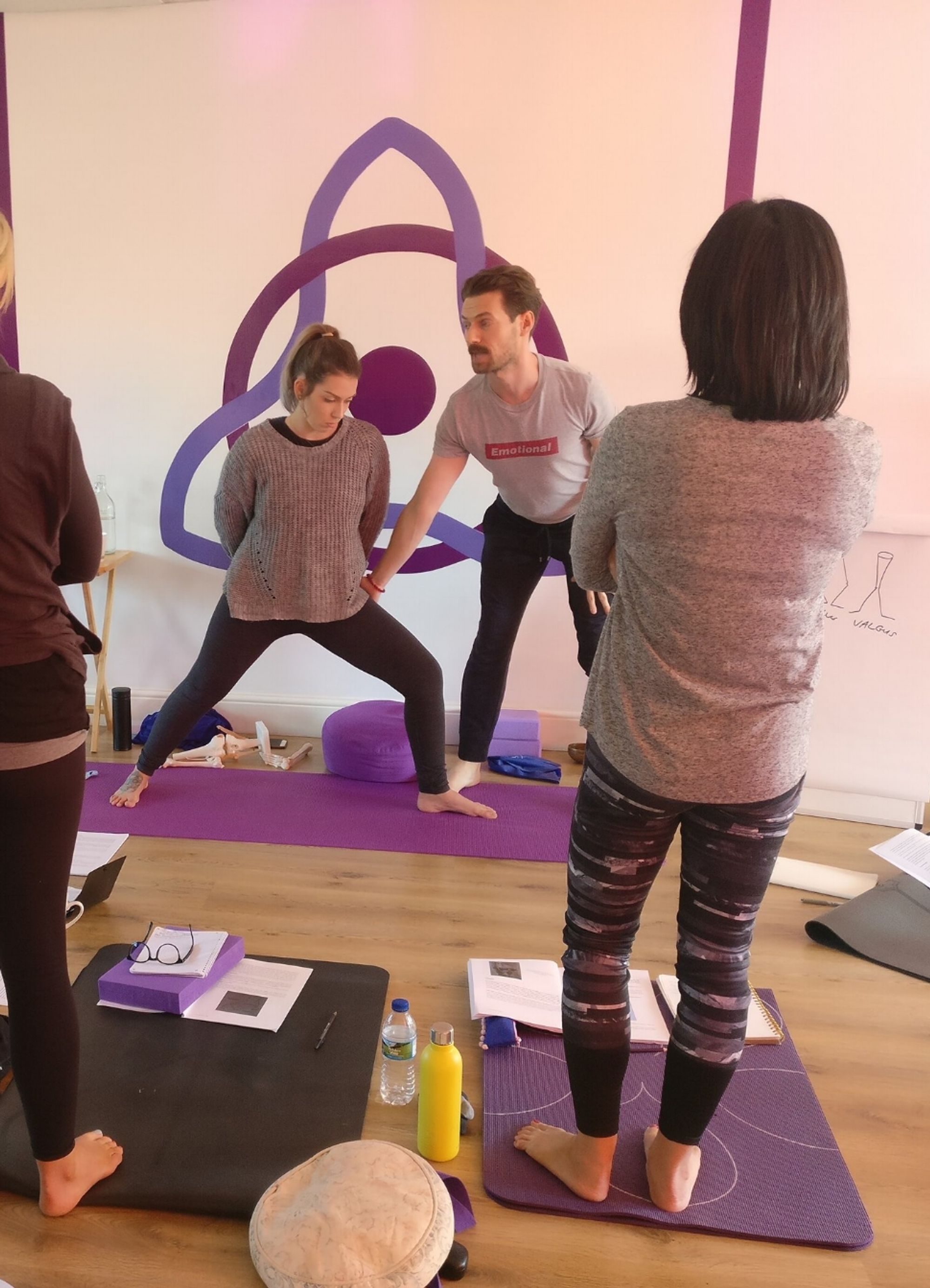 Yoga teacher with a student demonstrating alignment of the knee over the ankle