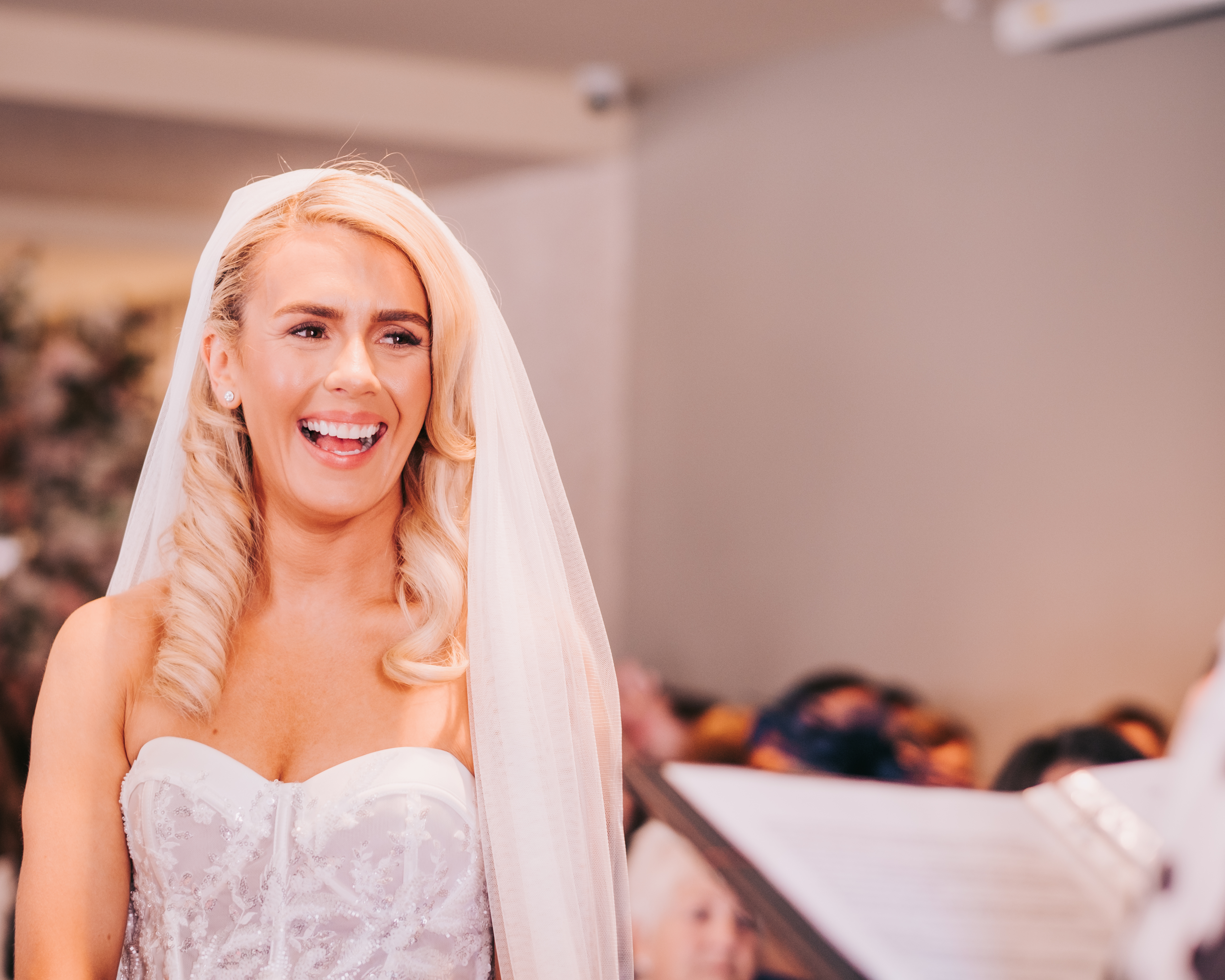 Bride laughing during her wedding ceremony at Citation in Merchant City, Glasgow, wearing a strapless embroidered dress and long veil. Bride laughing during her wedding ceremony at Citation in Merchant City, Glasgow, wearing a strapless embroidered dress and long veil.