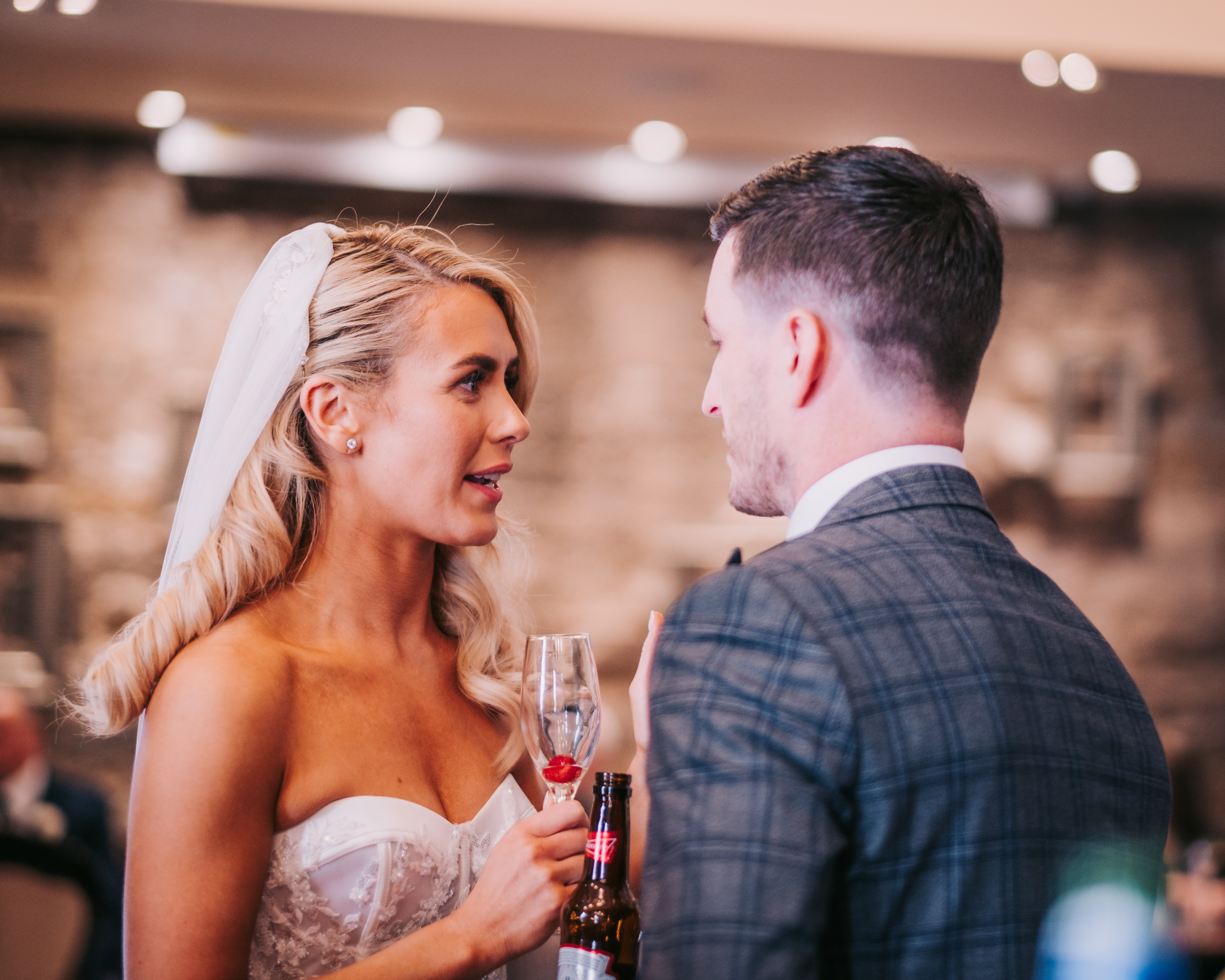 Bride and groom sharing a drink and conversation at the reception bar, candid moment. Bride and groom sharing a drink and conversation at the reception bar, candid moment.