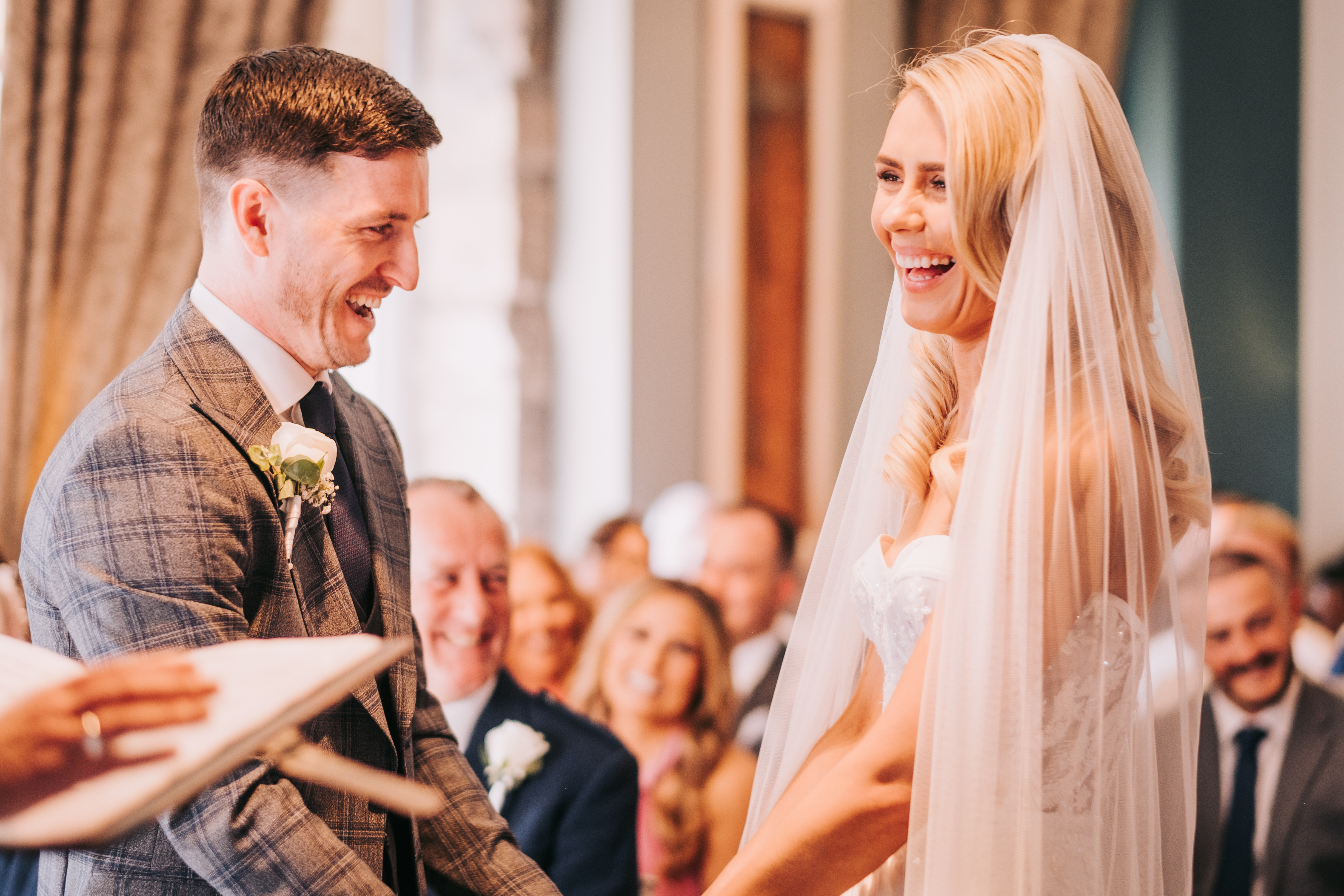 Bride and groom laughing during vows, guests smiling in background Bride and groom laughing during vows, guests smiling in background