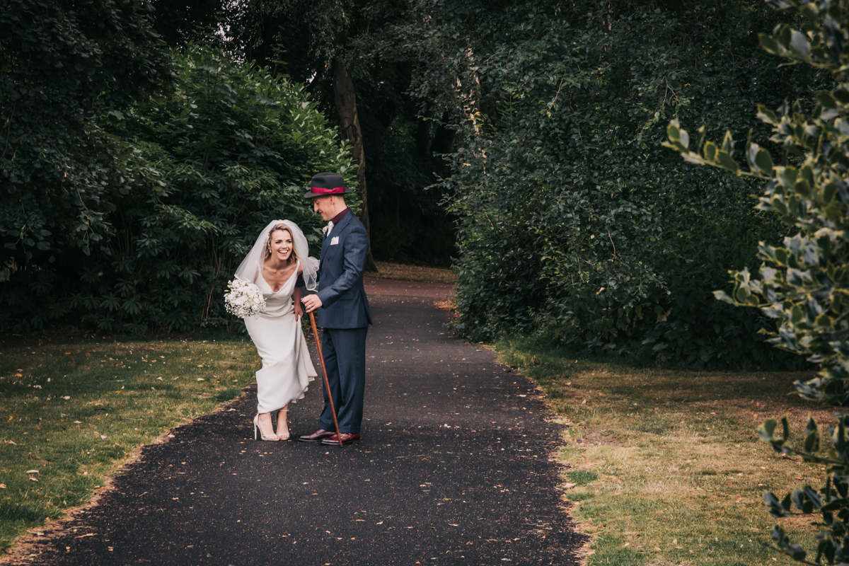 Bride and groom in Maxwell Park, Pollokshields Burgh Hall, Glasgow. Bride leaning forwards, laughing. Bride and groom in Maxwell Park, Pollokshields Burgh Hall, Glasgow. Bride leaning forwards, laughing.