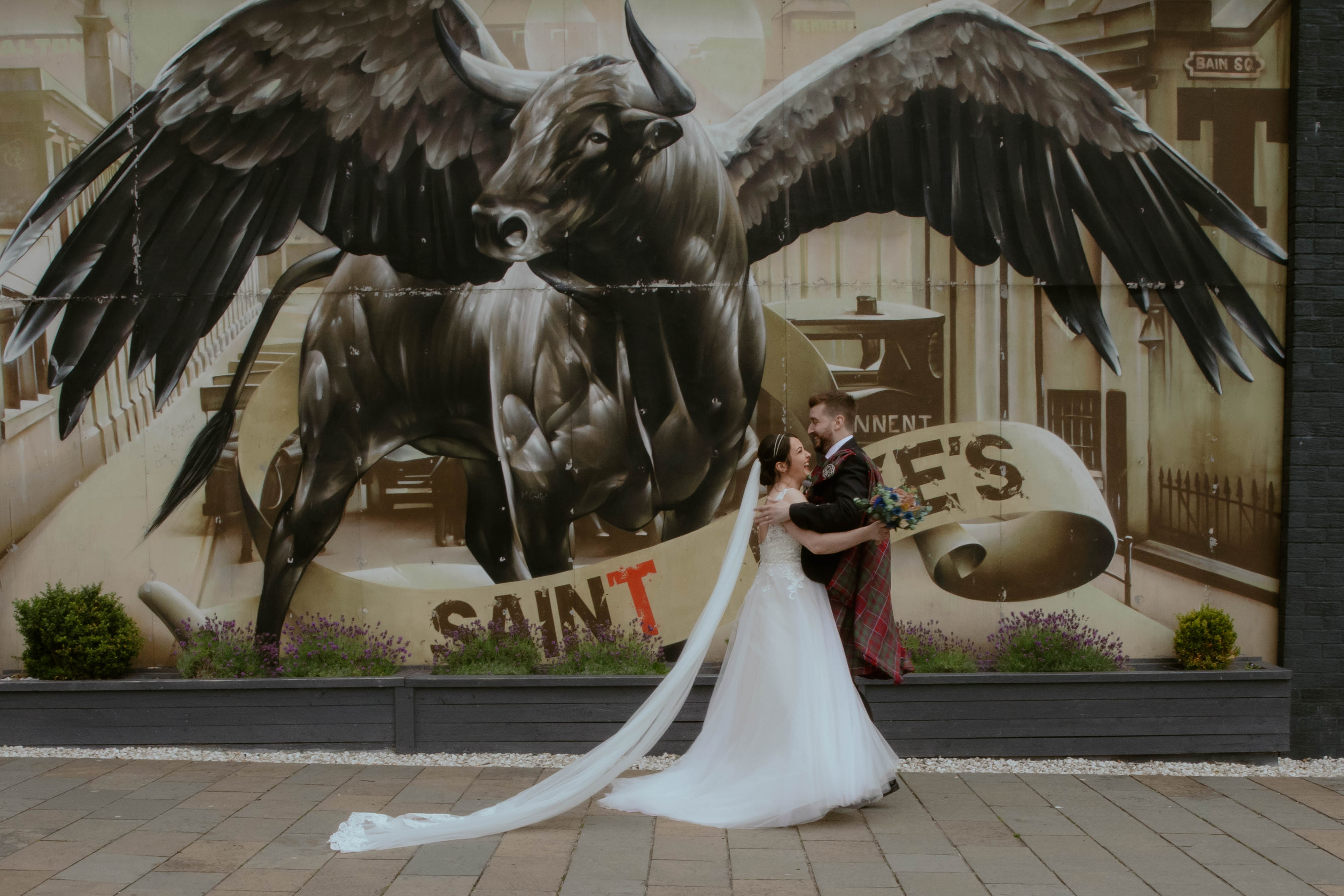 Bride and Groom running towards one another in front of the Winged Ox Mural, Saint Luke's, Glasgow. Bride and Groom running towards one another in front of the Winged Ox Mural, Saint Luke's, Glasgow.