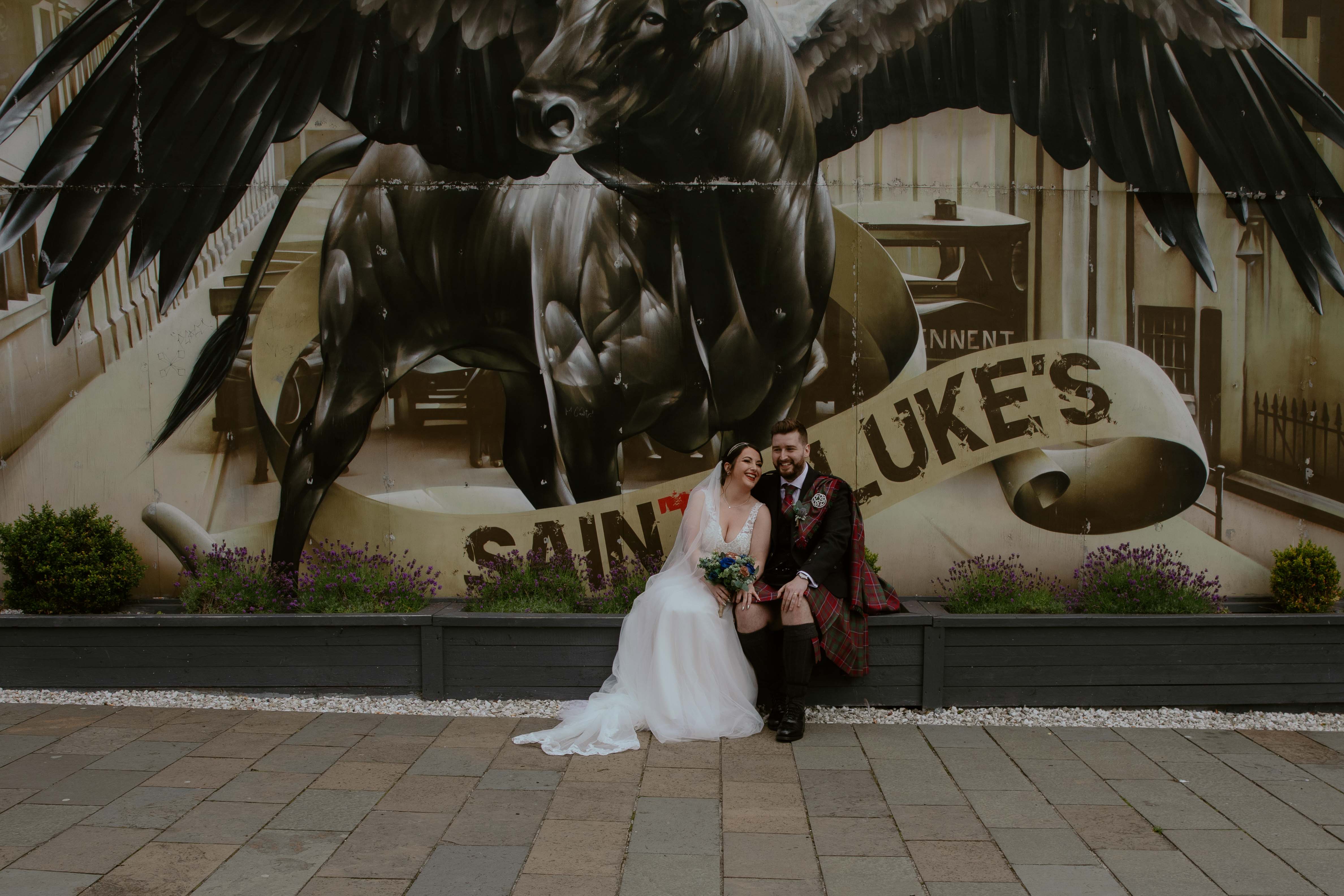 Bride and Groom sat in front of the Winged Ox Mural, Saint Luke's, Glasgow. Bride and Groom sat in front of the Winged Ox Mural, Saint Luke's, Glasgow.