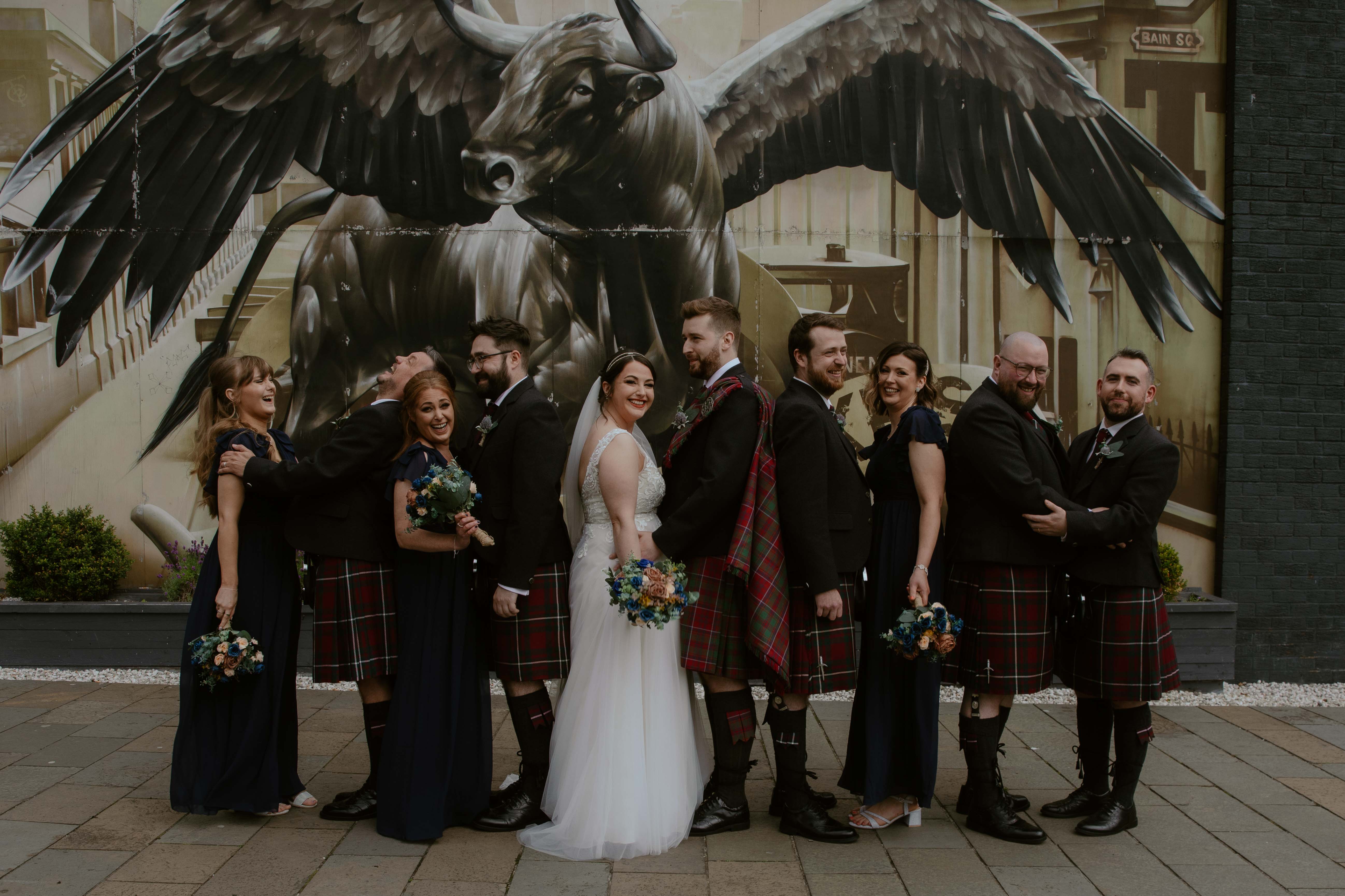 Group shot with Bride and Groom and bridal party in front of Winged Ox Mural, Saint Luke's, Glasgow. Group shot with Bride and Groom and bridal party in front of Winged Ox Mural, Saint Luke's, Glasgow.