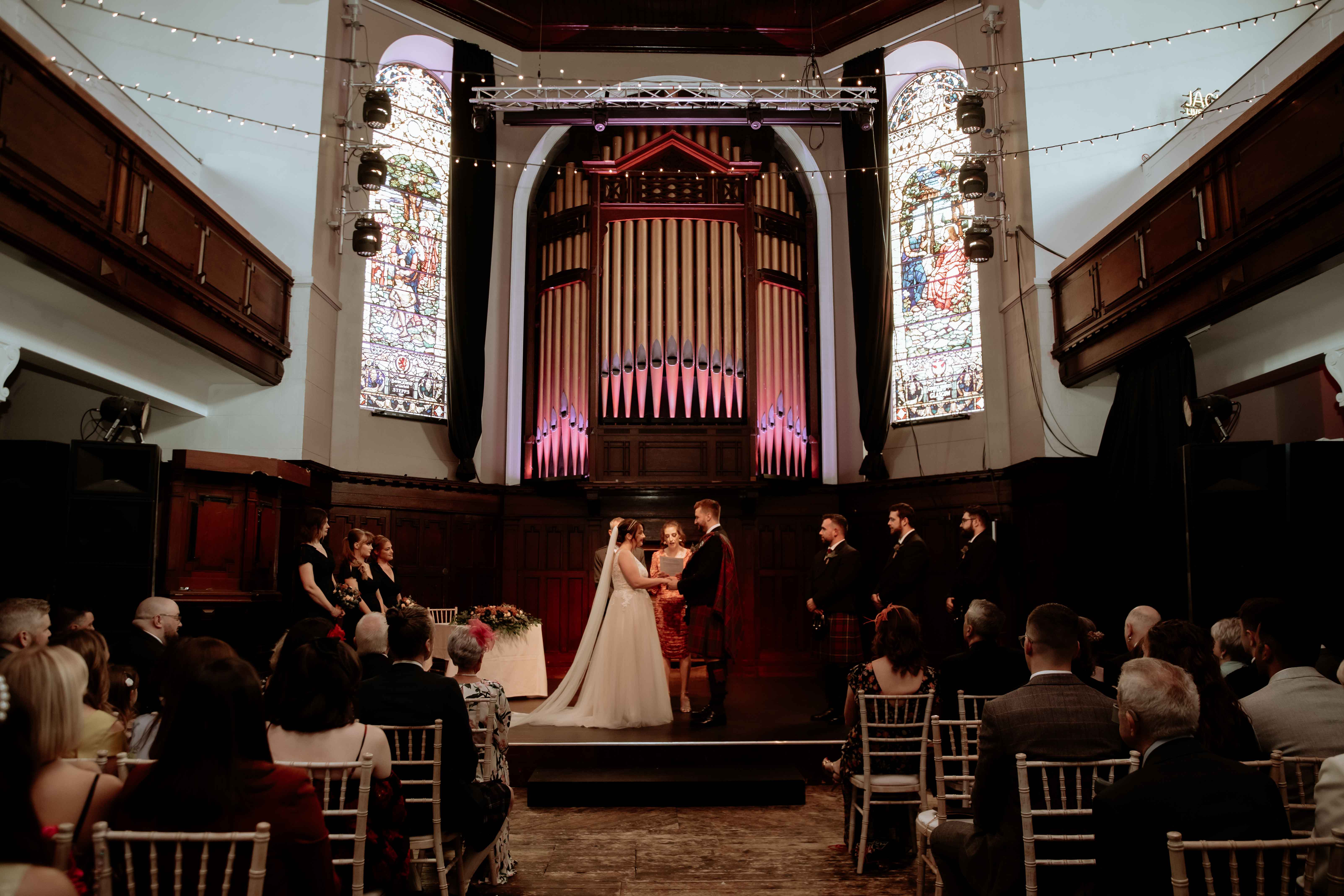Ellie and Dan on the stage during wedding vows in Saint Luke's, Glasgow. Ellie and Dan on the stage during wedding vows in Saint Luke's, Glasgow.