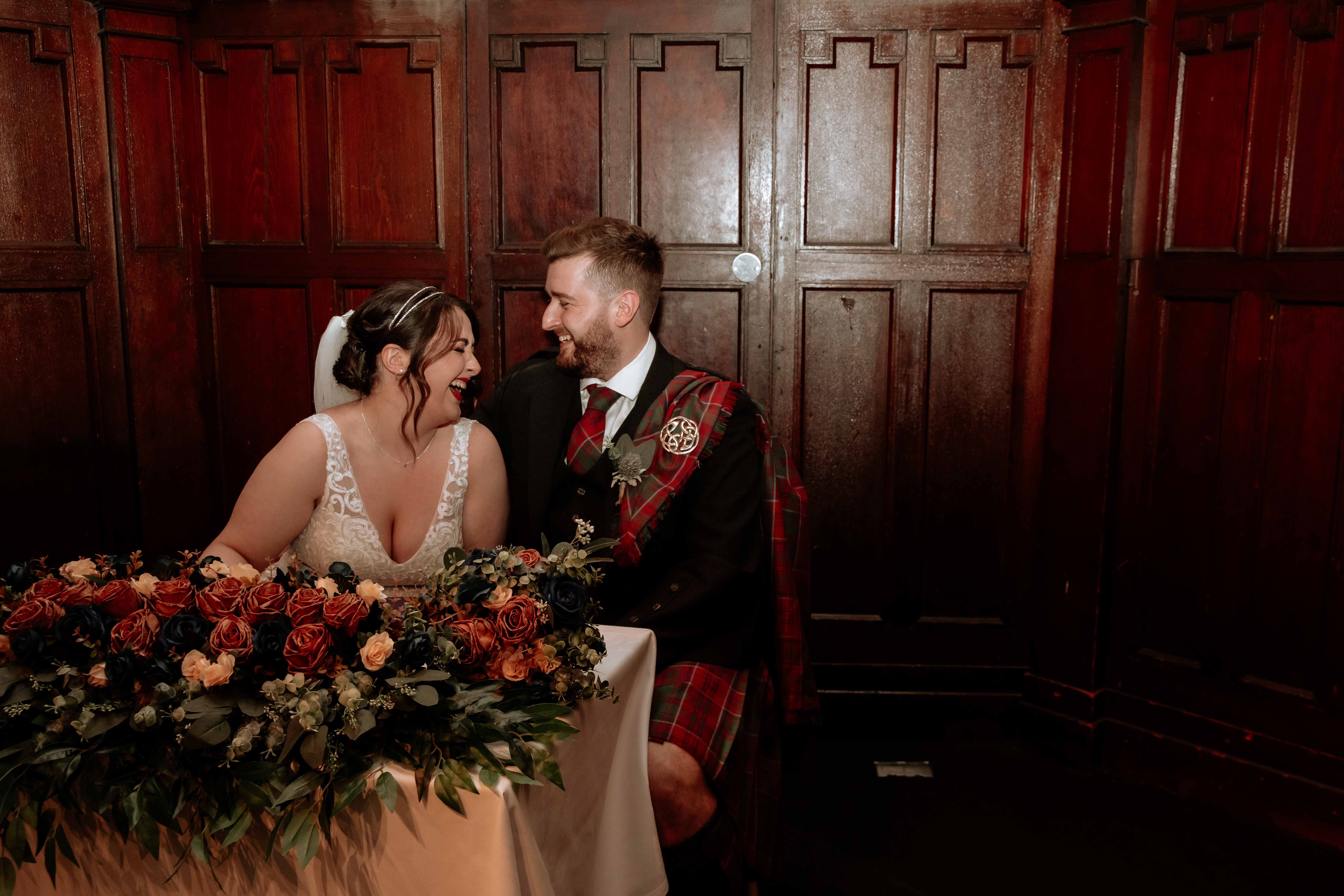 Bride and groom laughing while sitting down to sign register, St. Luke's, Glasgow. Bride and groom laughing while sitting down to sign register, St. Luke's, Glasgow.