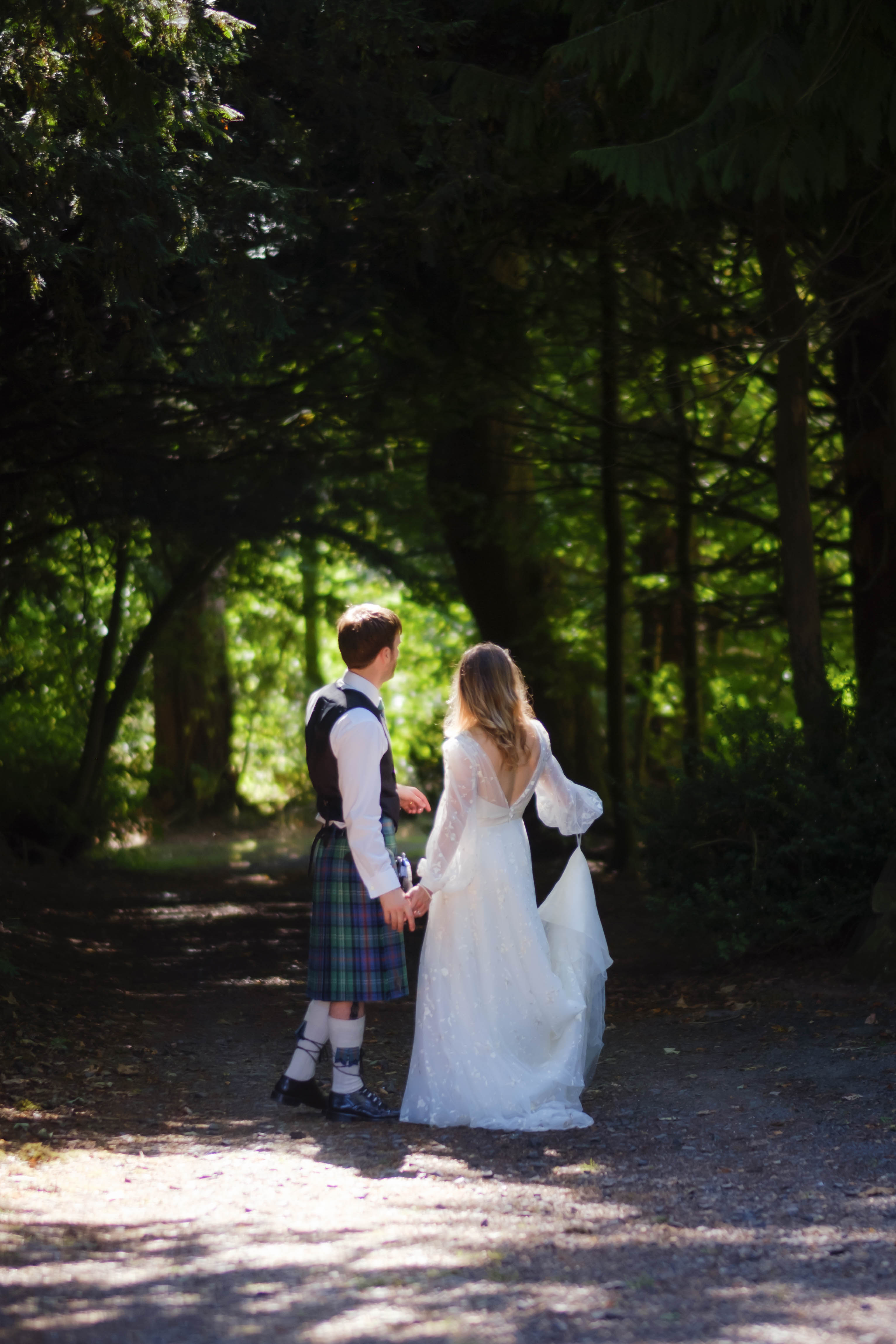 Bride and Groom standing in the forest, bride holding the loop of her wedding dress. Bride and Groom standing in the forest, bride holding the loop of her wedding dress.