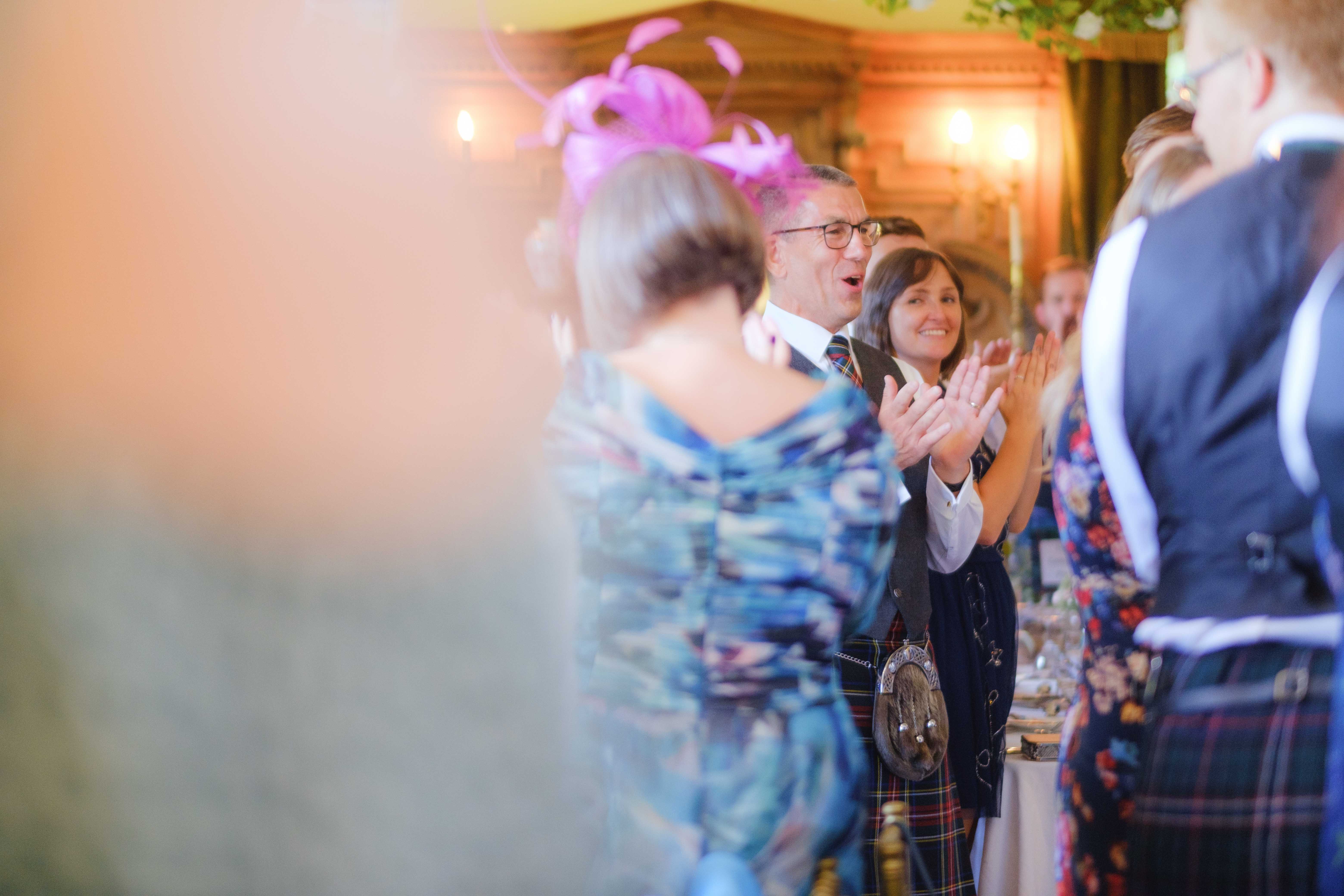 Father of the bride clapping with guests indoors. Father of the bride clapping with guests indoors.