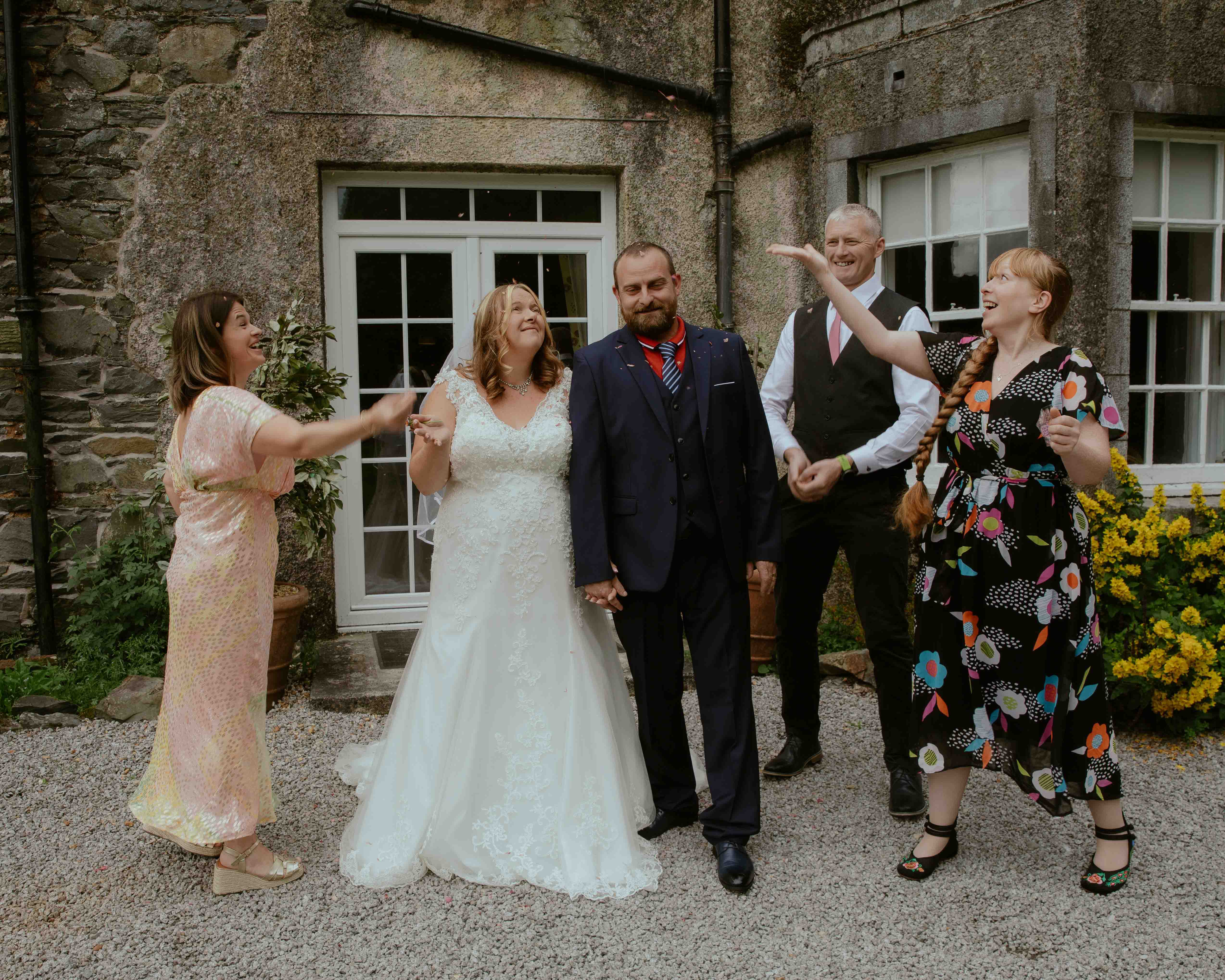 Bride and groom laughing while guests throw confetti at Creebridge House Hotel Bride and groom laughing while guests throw confetti at Creebridge House Hotel