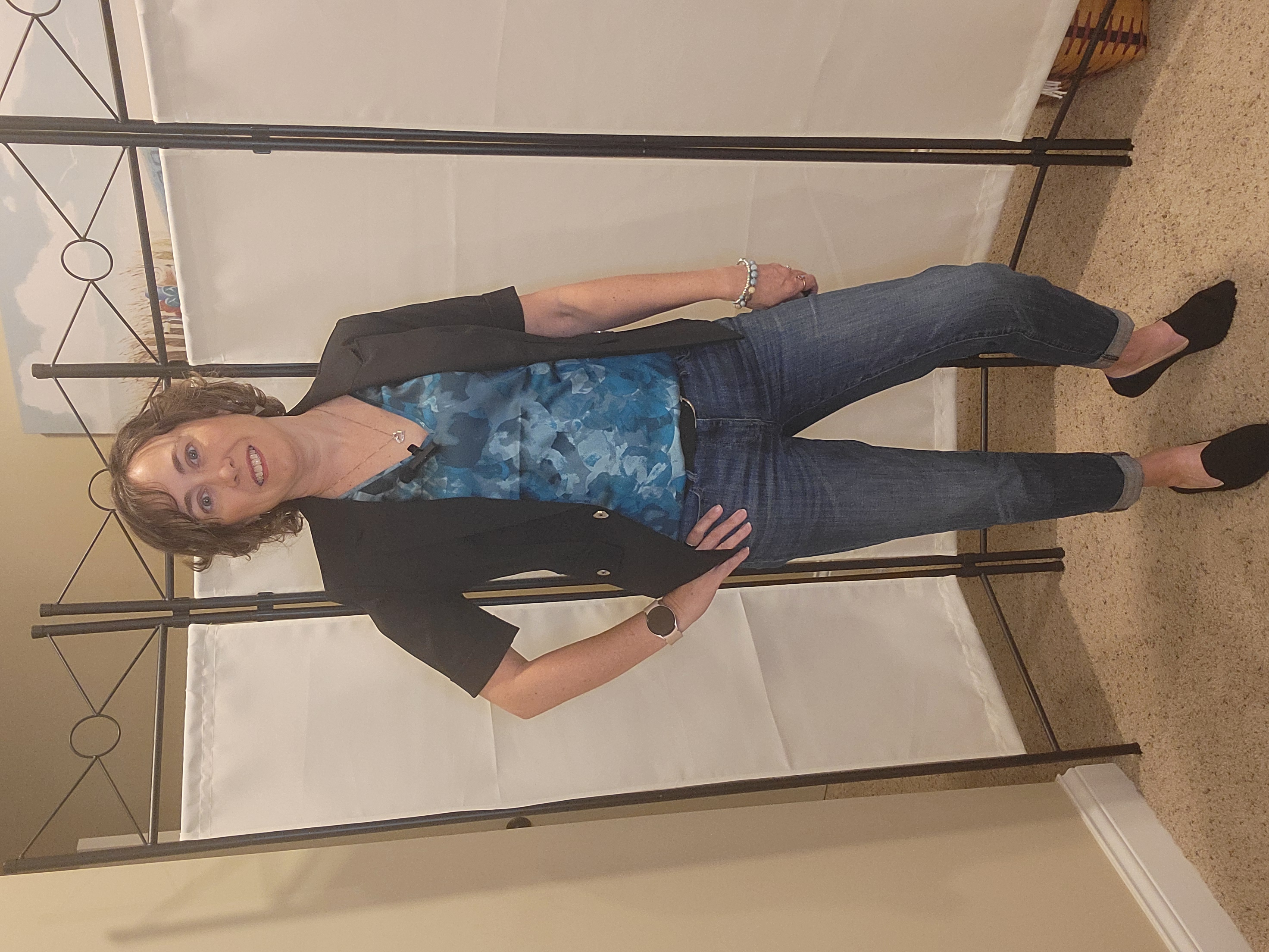 Chic casual outfit featuring a WHBM black short-sleeve blazer layered over a green printed v-neck top, paired with cuffed girlfriend jeans and classic black flats. A stylish mix of structured and relaxed pieces for everyday confidence.