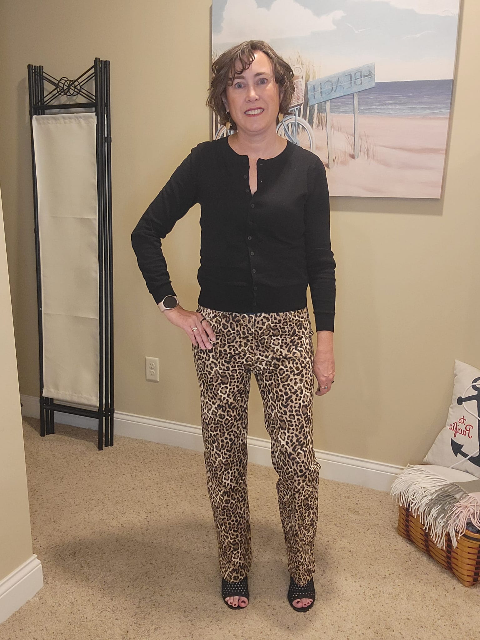 Jennifer Whitacre of Styled by Jenn wearing a Loft black cardigan paired with altered leopard print jeans, a brown stone statement necklace, and black Rothy’s flats — a stylish casual look that blends comfort with modern sophistication.
