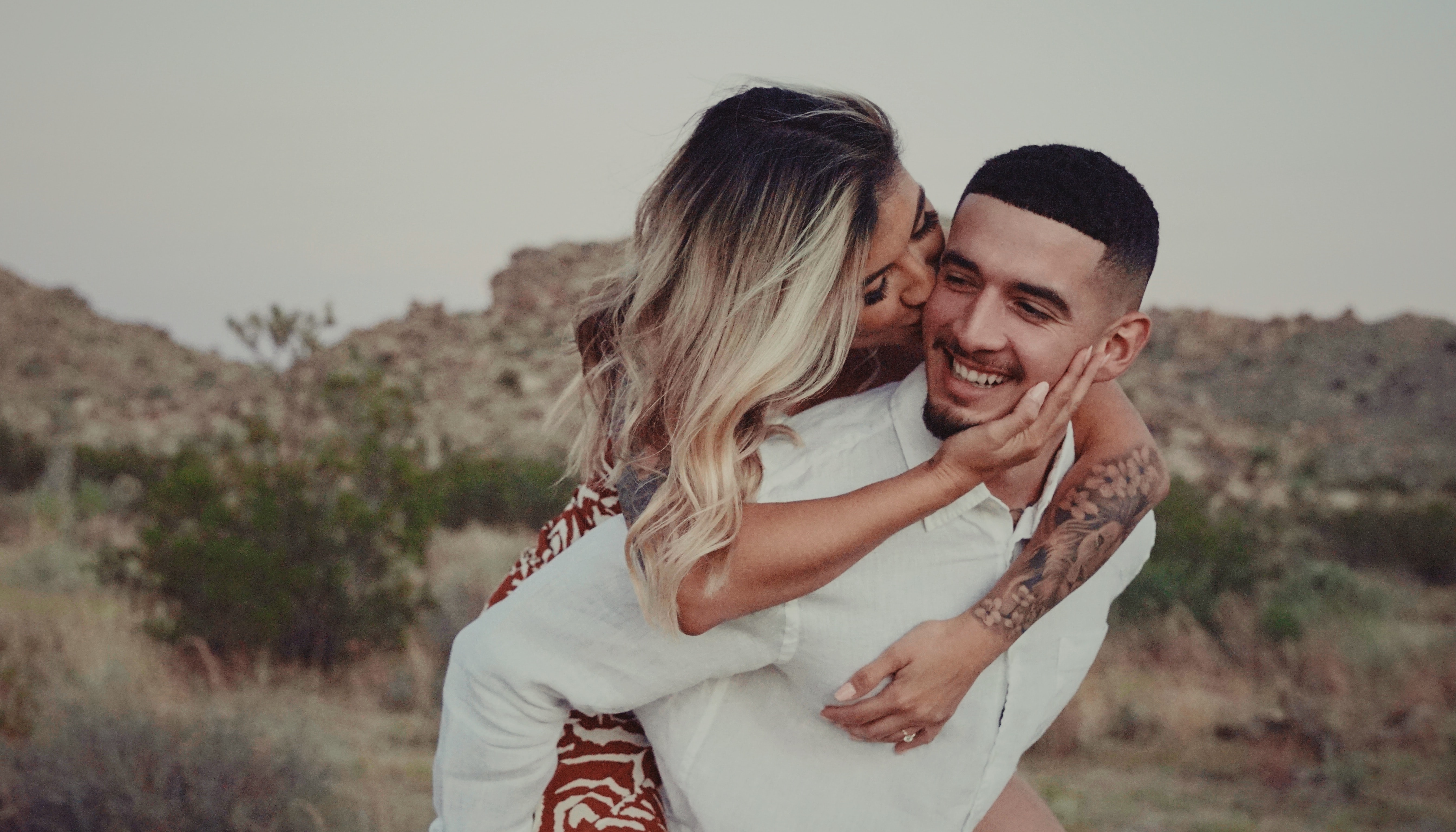 a woman hugs a man lovingly from behind