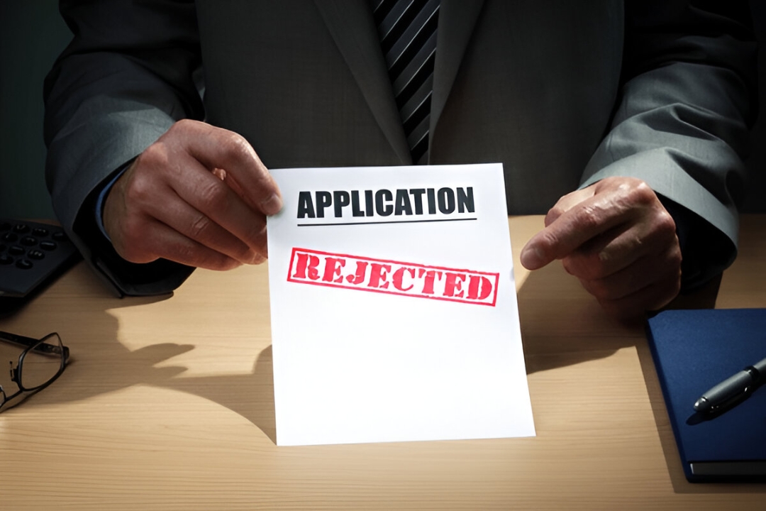 A businessman holding an "APPLICATION REJECTED" paper, representing challenges, but owner financing can provide solutions. A businessman holding an "APPLICATION REJECTED" paper, representing challenges, but owner financing can provide solutions.