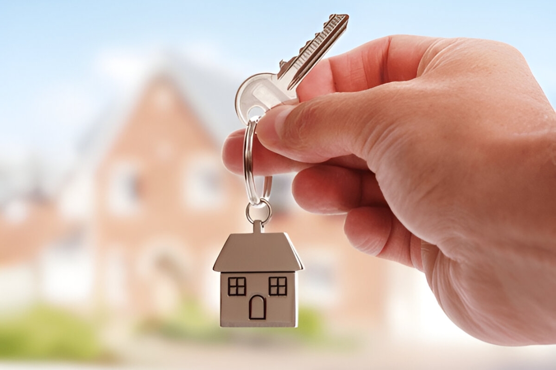 A hand holds a set of house keys with a house-shaped keychain, symbolizing new home ownership through owner financing. A hand holds a set of house keys with a house-shaped keychain, symbolizing new home ownership through owner financing.