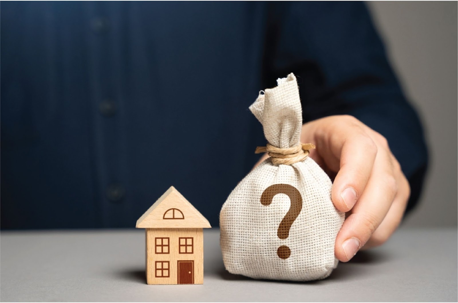 A wooden toy house sits next to a burlap sack with a question mark, symbolizing Non-bank home financing options via KBR Investing. A wooden toy house sits next to a burlap sack with a question mark, symbolizing Non-bank home financing options via KBR Investing.