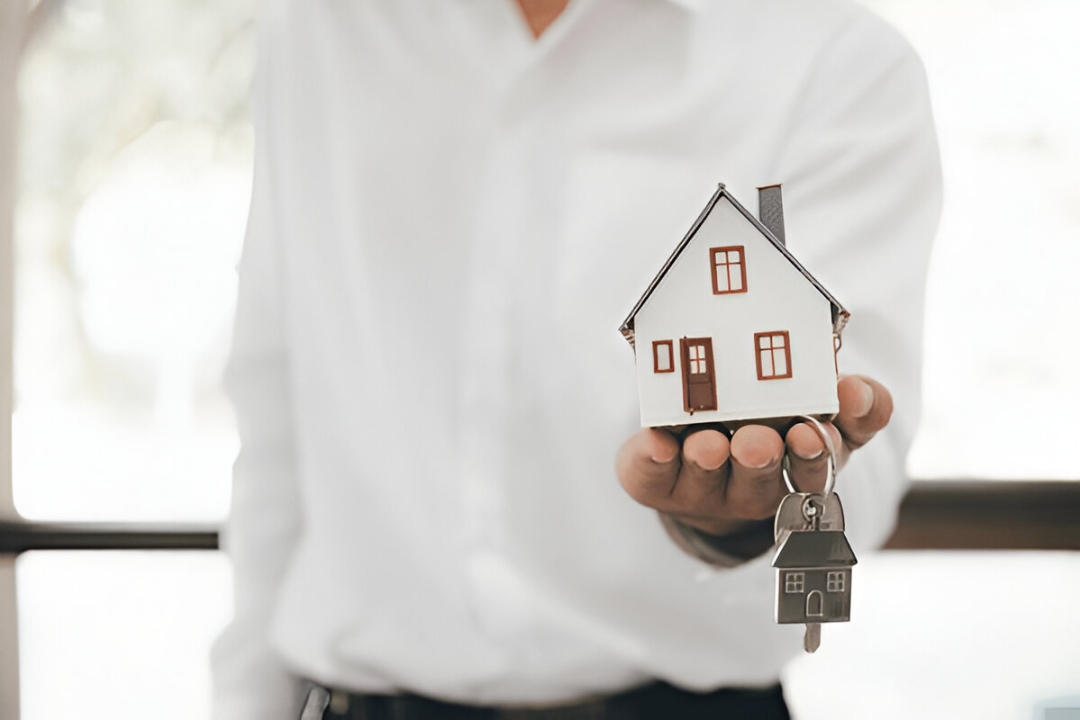  A realtor presents a miniature house with keys, enabling you to Buy a house with owner financing from KBR Investing.
