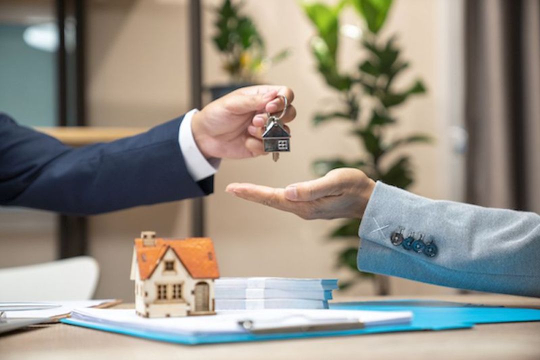  A hand presents house keys and a model house, showing the exchange of property for KBR Investing's Owner financing options.