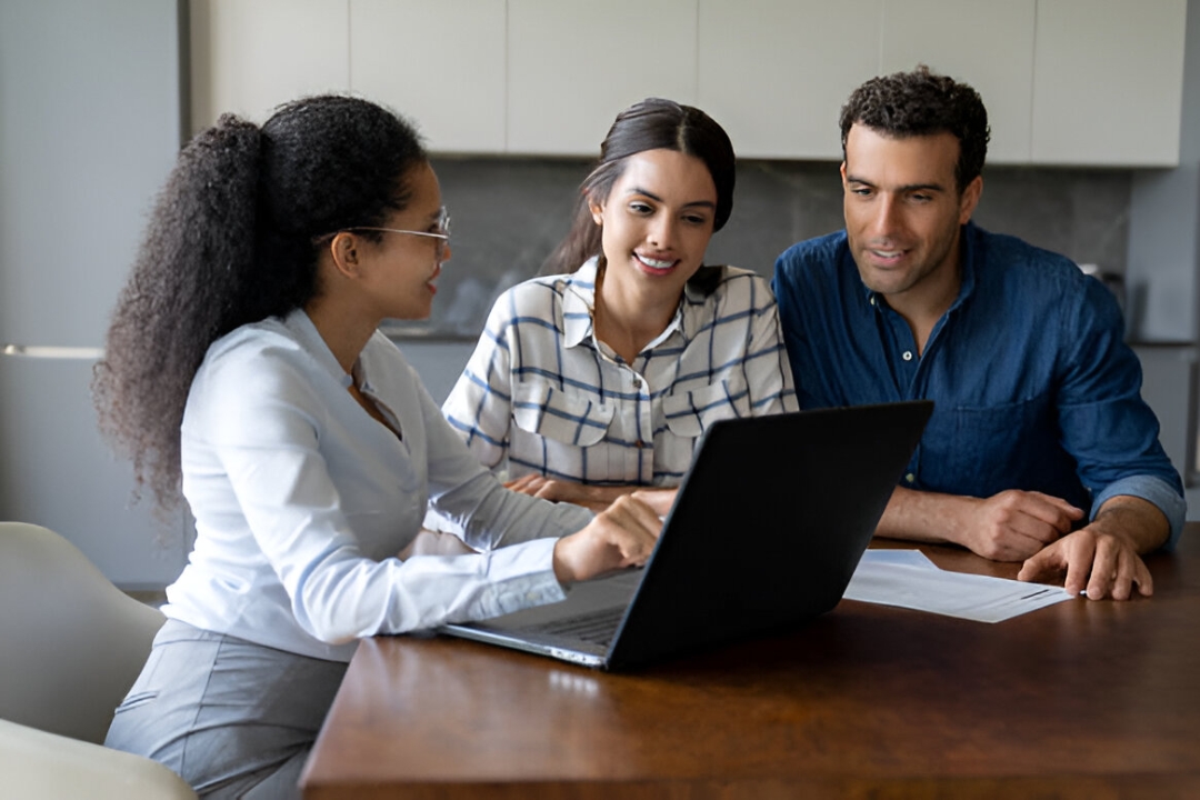  A smiling female real estate agent discusses Owner financing for first-time homebuyers with a couple at KBR Investing.